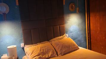 Un dormitorio con cama, mesita de noche y velador.