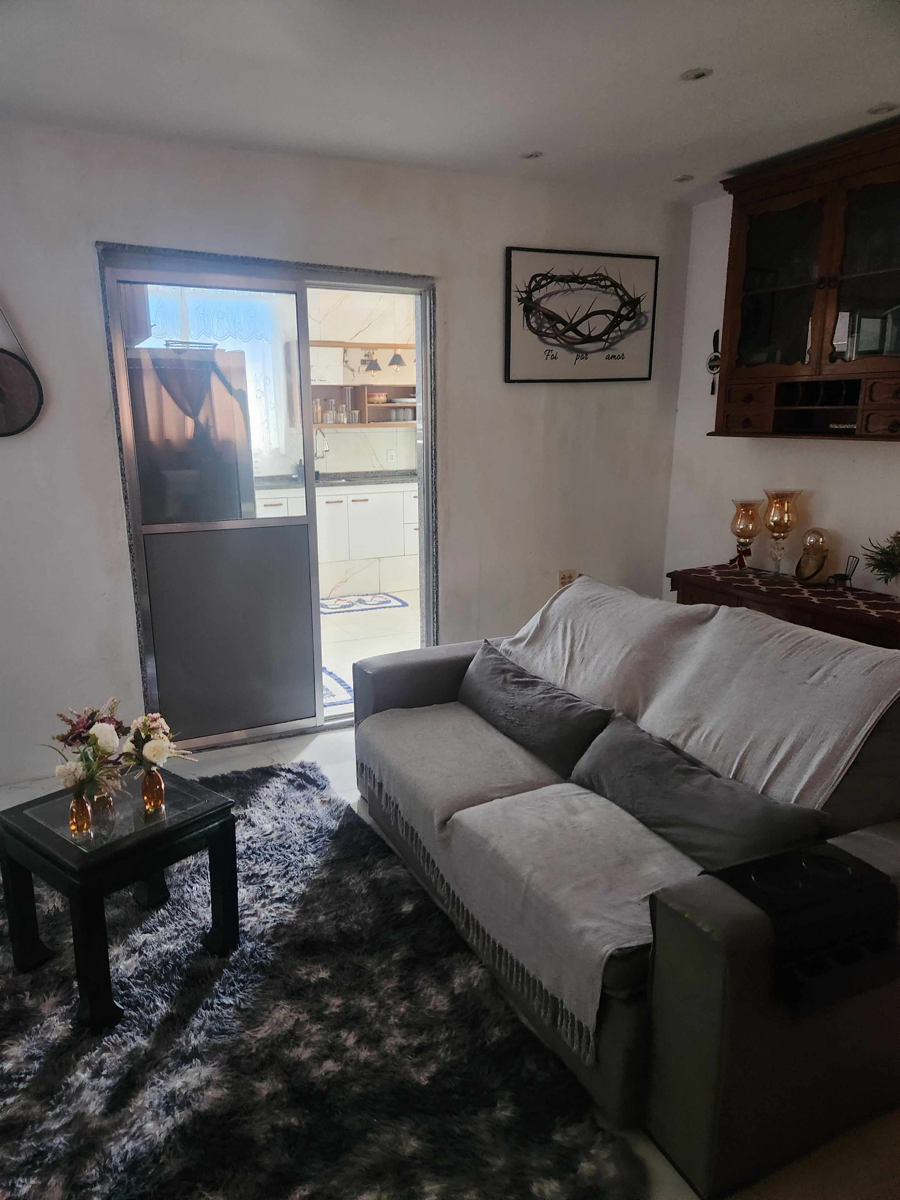 A living room with a sofa, a glass coffee table, and a rug. There is a door leading to a balcony.
