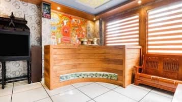 A reception area with a wooden counter, a television, and a mural on the wall.