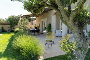 Una veranda con tavolo e sedie, un barbecue e un'area salotto coperta.