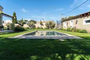 A rectangular swimming pool surrounded by a well-maintained lawn, with a house and a pergola in the background. - New Listing (Aureille)