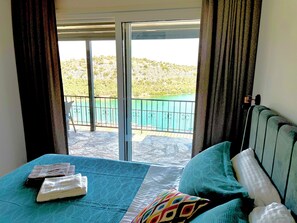 A room with a bed, a window with a view of a balcony, and a door. - Spectacular sea view cozy 3-bedrooms house with AC in tranquil Antik City İasos (Muğla)