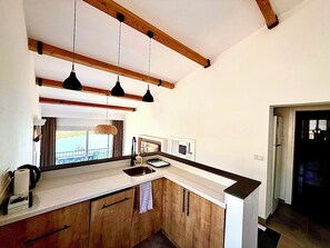 A kitchen with wooden cabinets, a countertop, and pendant lights. - Spectacular sea view cozy 3-bedrooms house with AC in tranquil Antik City İasos (Muğla)