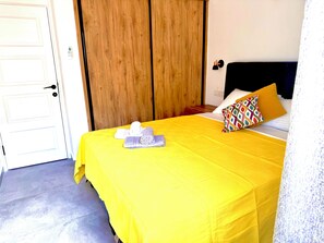 A hotel room with a bed, a wooden wardrobe, a bedside table, and a door. - Spectacular sea view cozy 3-bedrooms house with AC in tranquil Antik City İasos (Muğla)