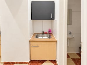 A compact kitchen with a stainless steel sink, a wooden countertop, a black cabinet, and a small storage drawer. - Stay Awhile Vienna 2BR with Living Room (Wien)