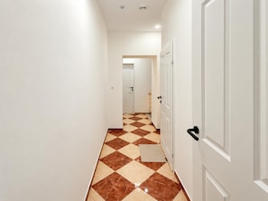 A hallway with a checkered floor pattern, white walls, and doors. - Stay Awhile Vienna 2BR with Living Room (Wien)