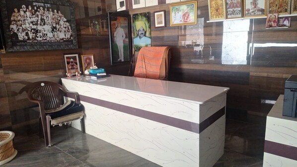 A reception desk with a chair, framed pictures, and a poster on the wall.