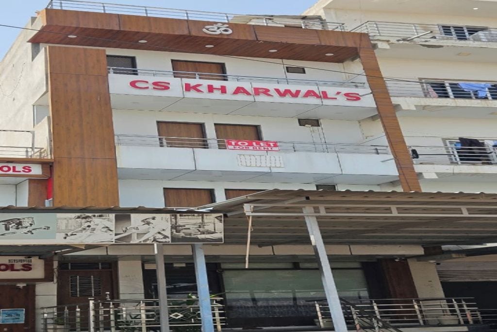 A multi-story building with a sign for 'CS Kharwal's' and a 'TO LET FOR RENT' sign.