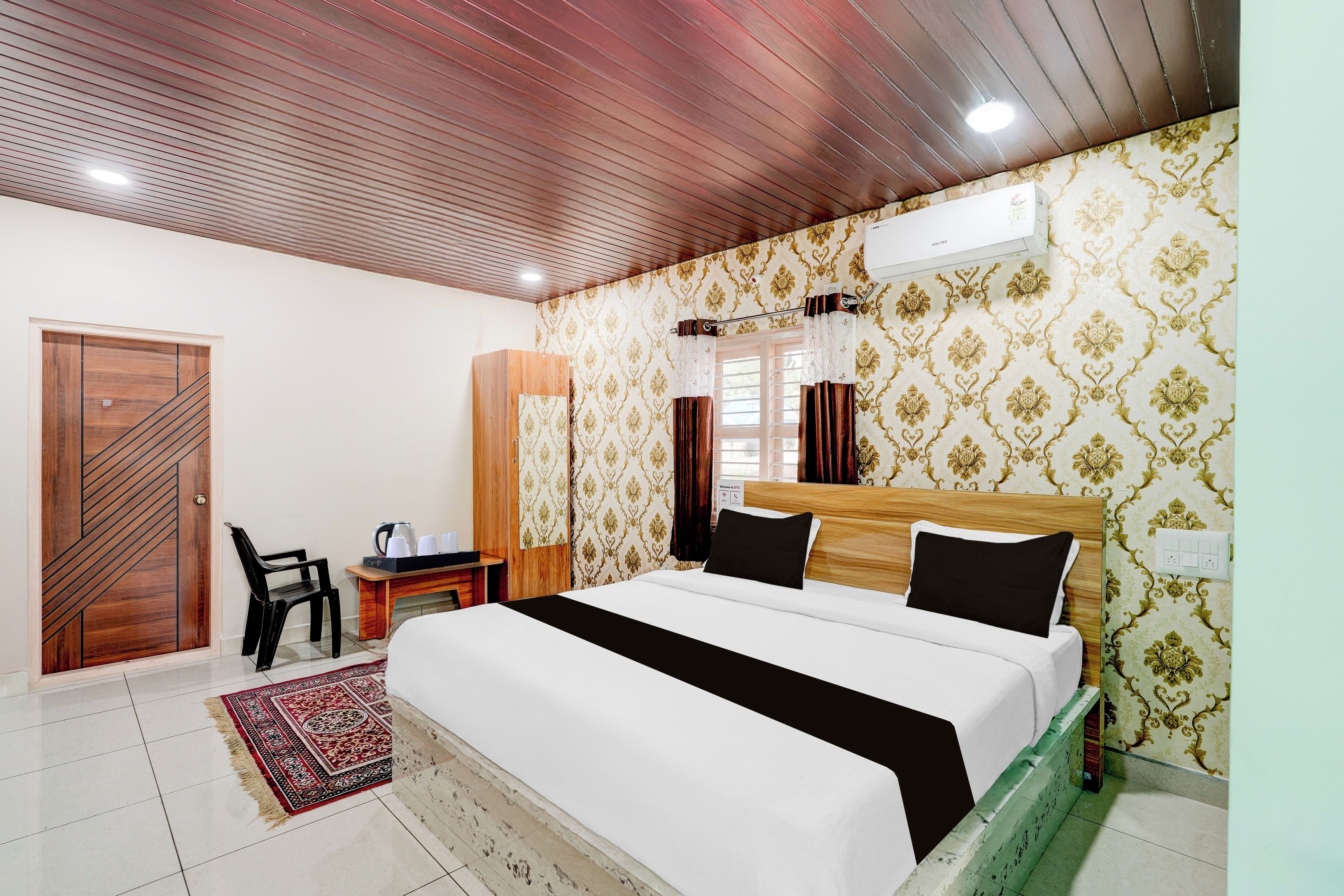 Una habitación de hotel con una cama, un escritorio, una silla y un armario.