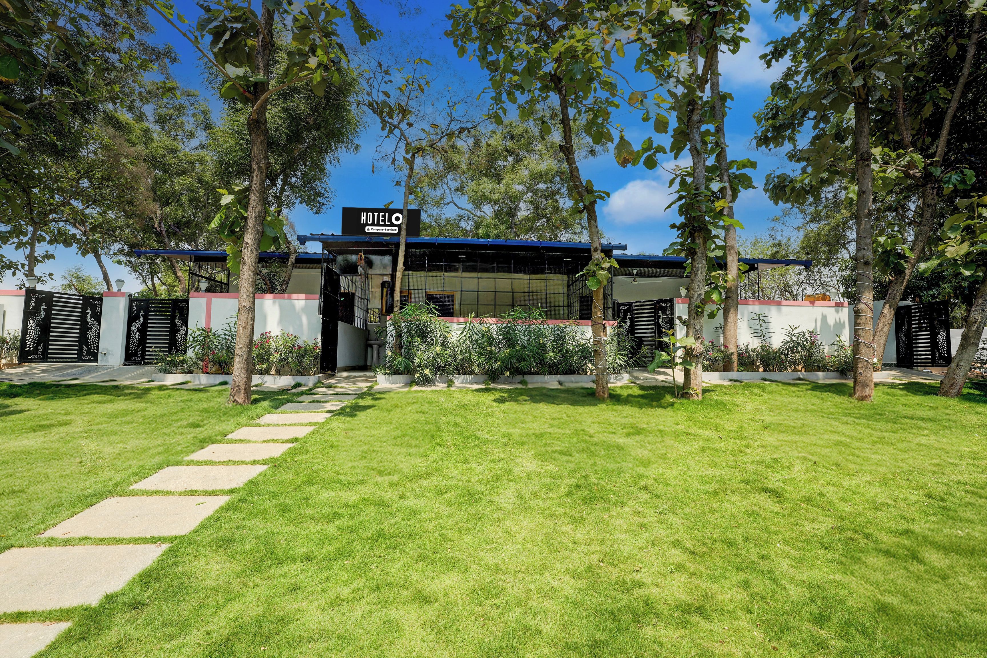 A hotel with a clear entrance, a signboard, and a well-maintained lawn.