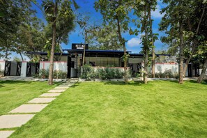 A hotel with a clear entrance, a signboard, and a well-maintained lawn.
