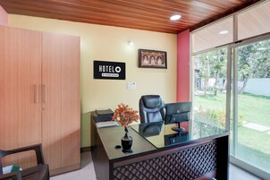 A hotel reception desk with a framed picture, a sign indicating the hotel name, and a view of the outdoors.