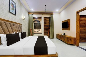Ein Hotelzimmer mit einem großen Bett, einem Fernseher, einer Holzkabine und einem Balkon mit Blick.