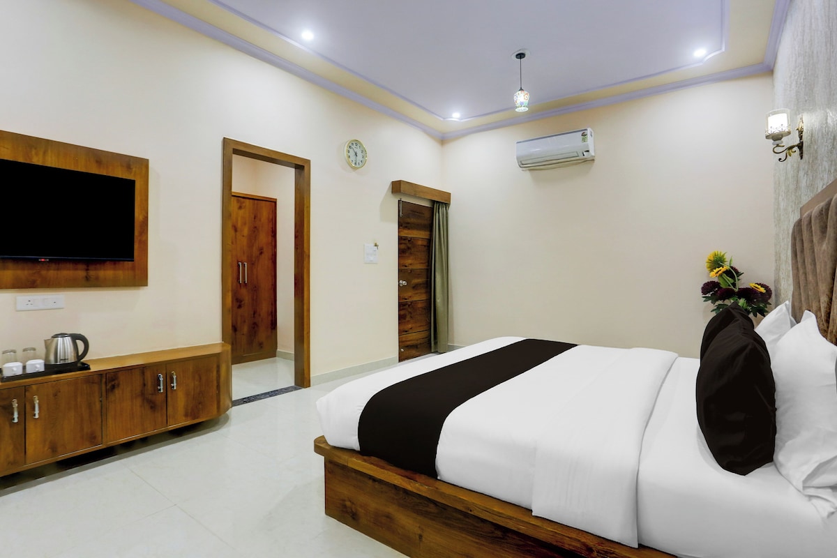 A bedroom with a bed, a TV, a wooden cabinet, and a clock on the wall.