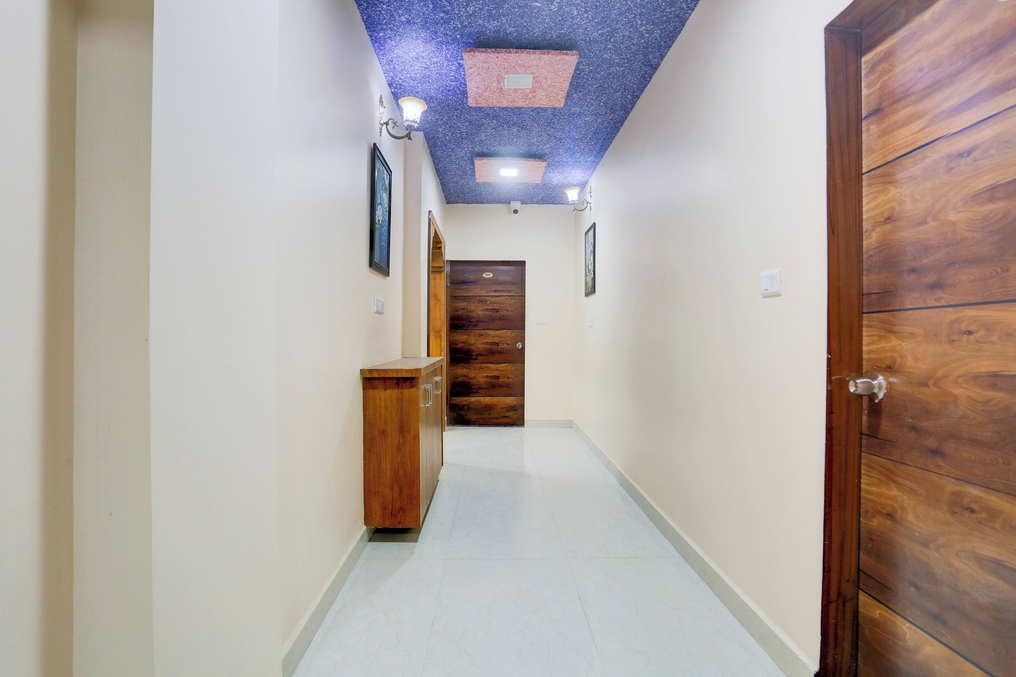 Un pasillo con una puerta de madera, un armario y un techo con un diseño azul y rojo.