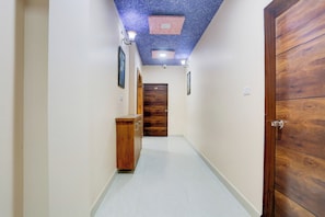 Un pasillo con una puerta de madera, un armario y un techo con un diseño azul y rojo.