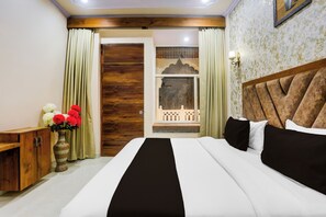 Ein Hotelzimmer mit einem Bett, einem Holzschrank, einer Vase mit Blumen und Blick auf einen Balkon.