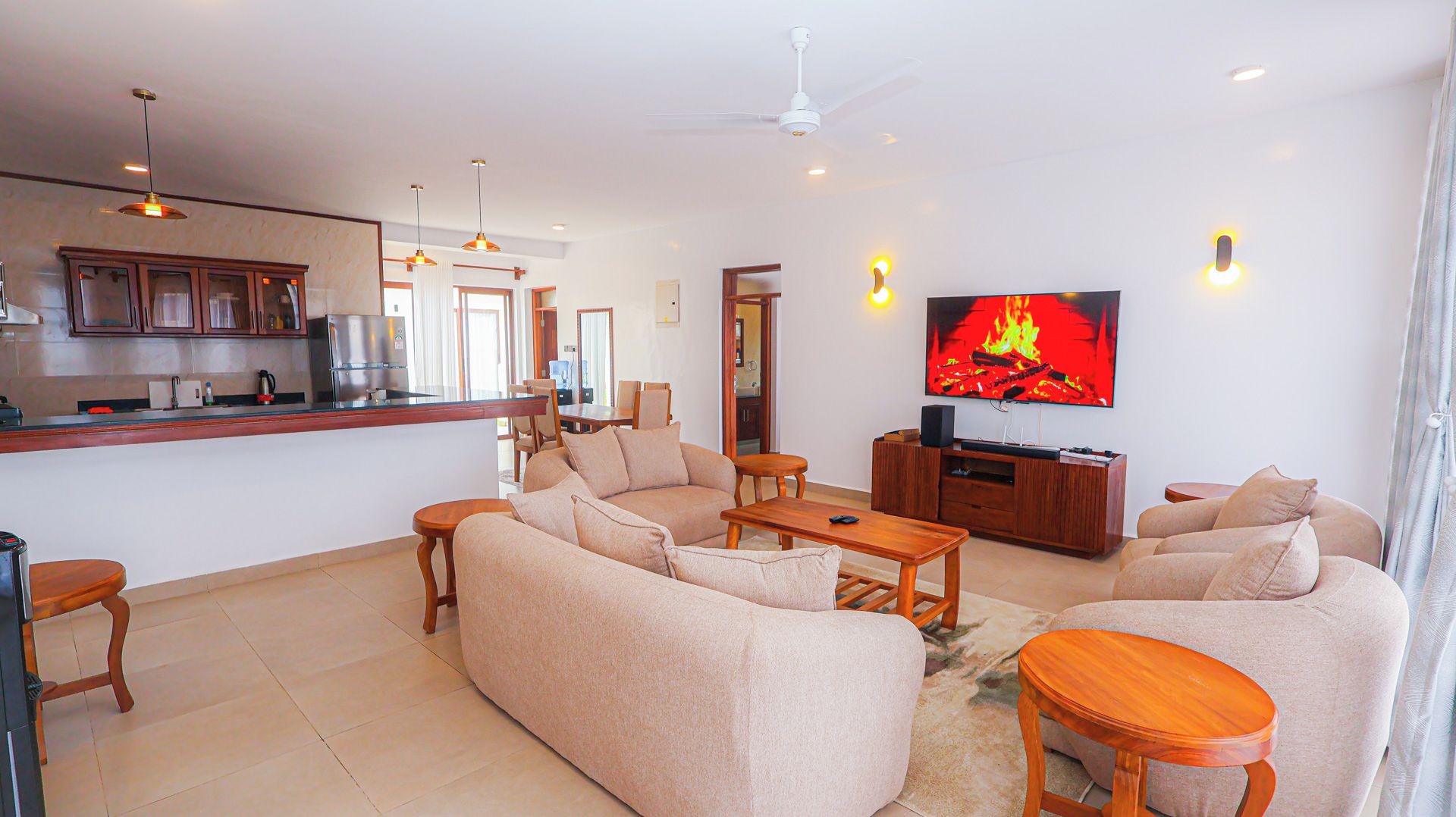 A modern living room with a sofa set, a coffee table, and a TV displaying a fire.