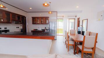 A modern kitchen with a central island, wooden cabinets, and pendant lighting.