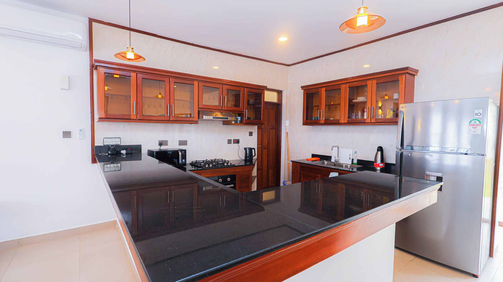 Una cocina moderna con armarios de madera, encimera negra y refrigerador de acero inoxidable.