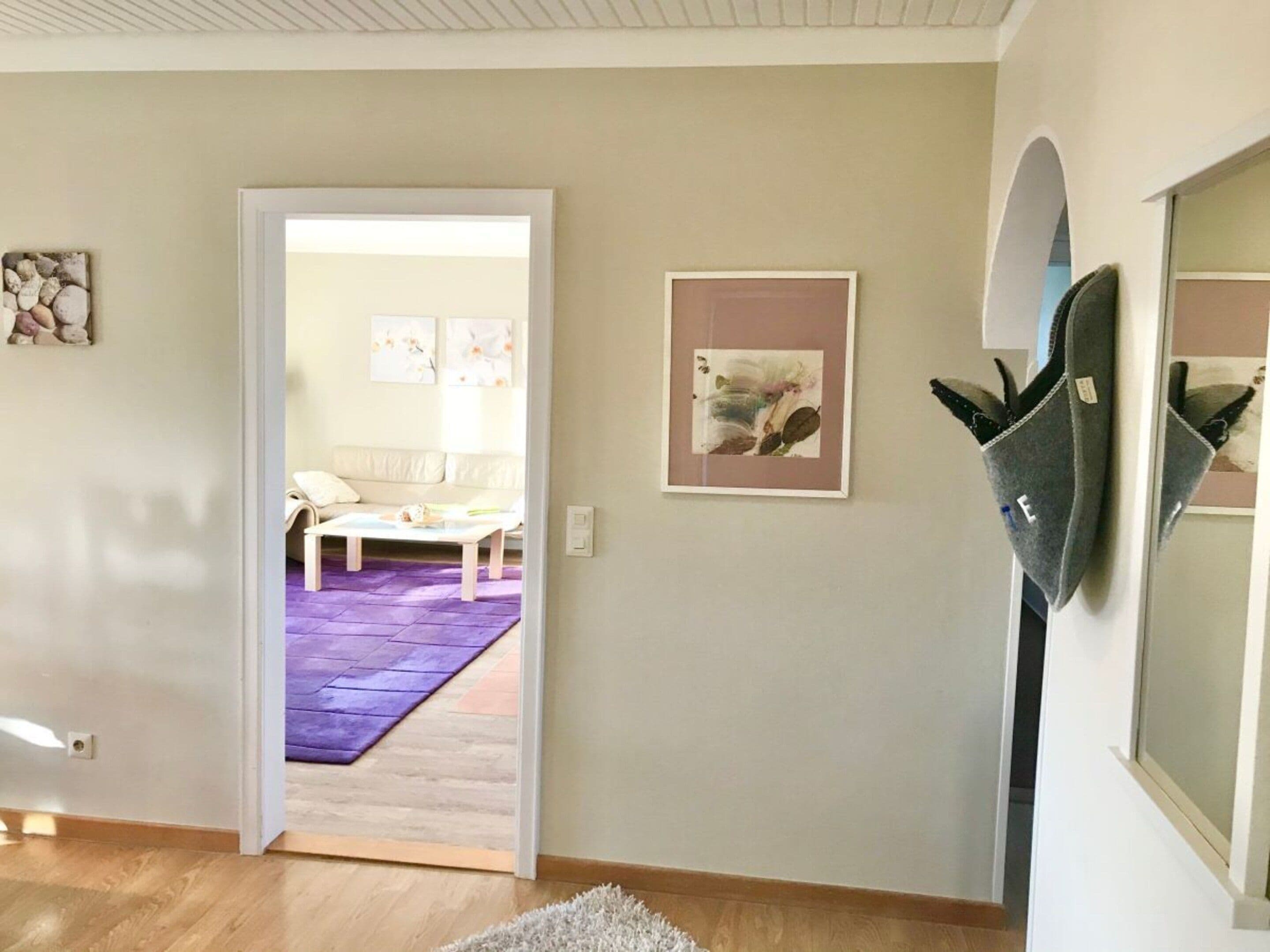 An interior space with a doorway leading to a room with a purple mat, a white sofa, and a framed picture on the wall.