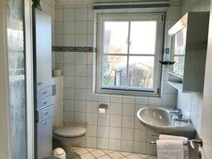 A bathroom with a toilet, sink, and window. - Haus Heike - Holiday Apartment Ground Floor (Utersum)