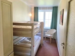 Dormitorio con literas, una silla y un radiador.