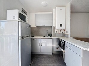 A compact kitchen with stainless steel appliances, a built-in microwave, and a water heater. - Studio for 4 ppl near the sea (Agde)
