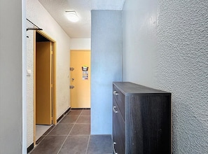 A hallway with a wooden door, a cabinet, and a wall with a textured surface. - Studio for 4 ppl near the sea (Agde)