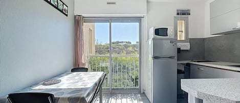 A compact kitchen with a refrigerator, microwave, and a small dining area with a table and chairs.