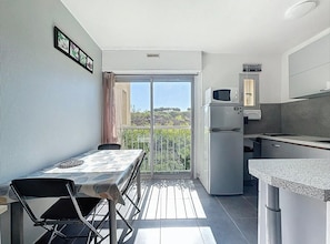 A compact kitchen with a refrigerator, microwave, and a small dining area with a table and chairs. - Studio for 4 ppl near the sea (Agde)
