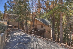 A two-story building with a wooden deck and a staircase leading to the upper level. - Serenity Treehouse | Forest Views | National Forest Trail & Sledding Access (Big Bear Lake)