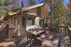 A wooden deck with a dining table and benches, surrounded by a deck railing. - Serenity Treehouse | Forest Views | National Forest Trail & Sledding Access (Big Bear Lake)