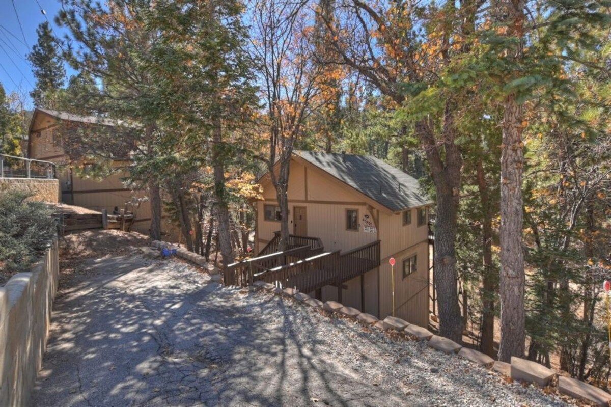 A two-story building with a wooden deck and a staircase leading to the upper level.