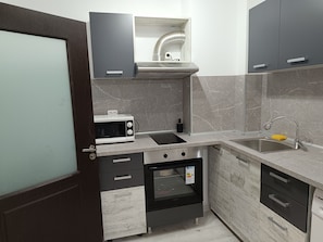 A compact kitchen with a microwave, oven, and sink. - One-Bedroom Apartment-14 Filip Makedonski 49B (Plovdiv)