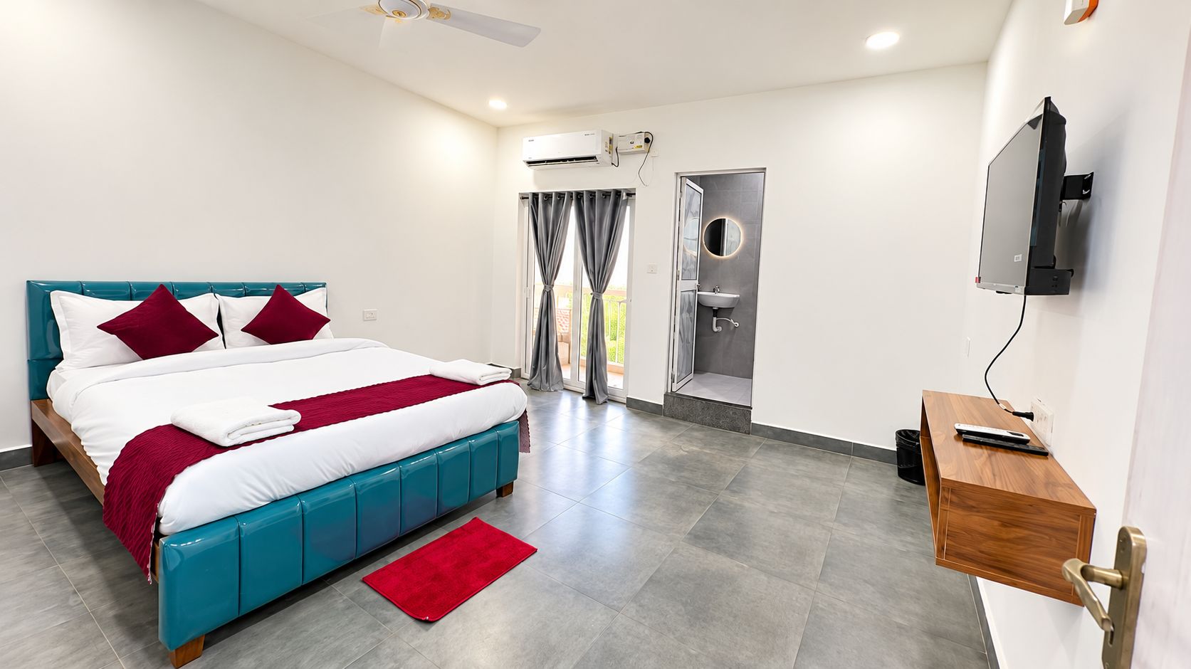 Quarto de hotel moderno com cama, escrivaninha e televisão.