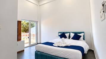 Un dormitorio moderno con una cama grande, un ventilador de techo y vistas al exterior a través de una puerta corrediza.