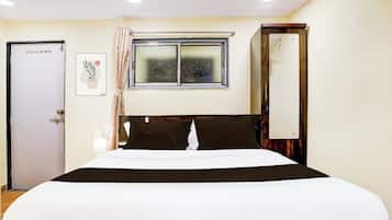 Une chambre d’hôtel avec un lit, une fenêtre donnant sur un paysage agréable, une porte et un luminaire fixé au mur.
