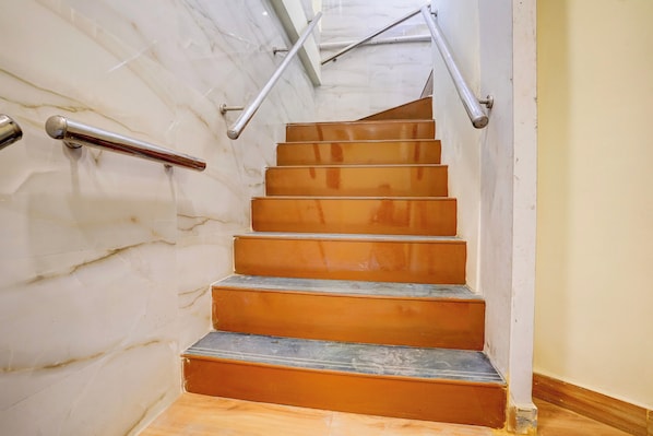 Una escalera con barandillas metálicas y un muro de mármol.