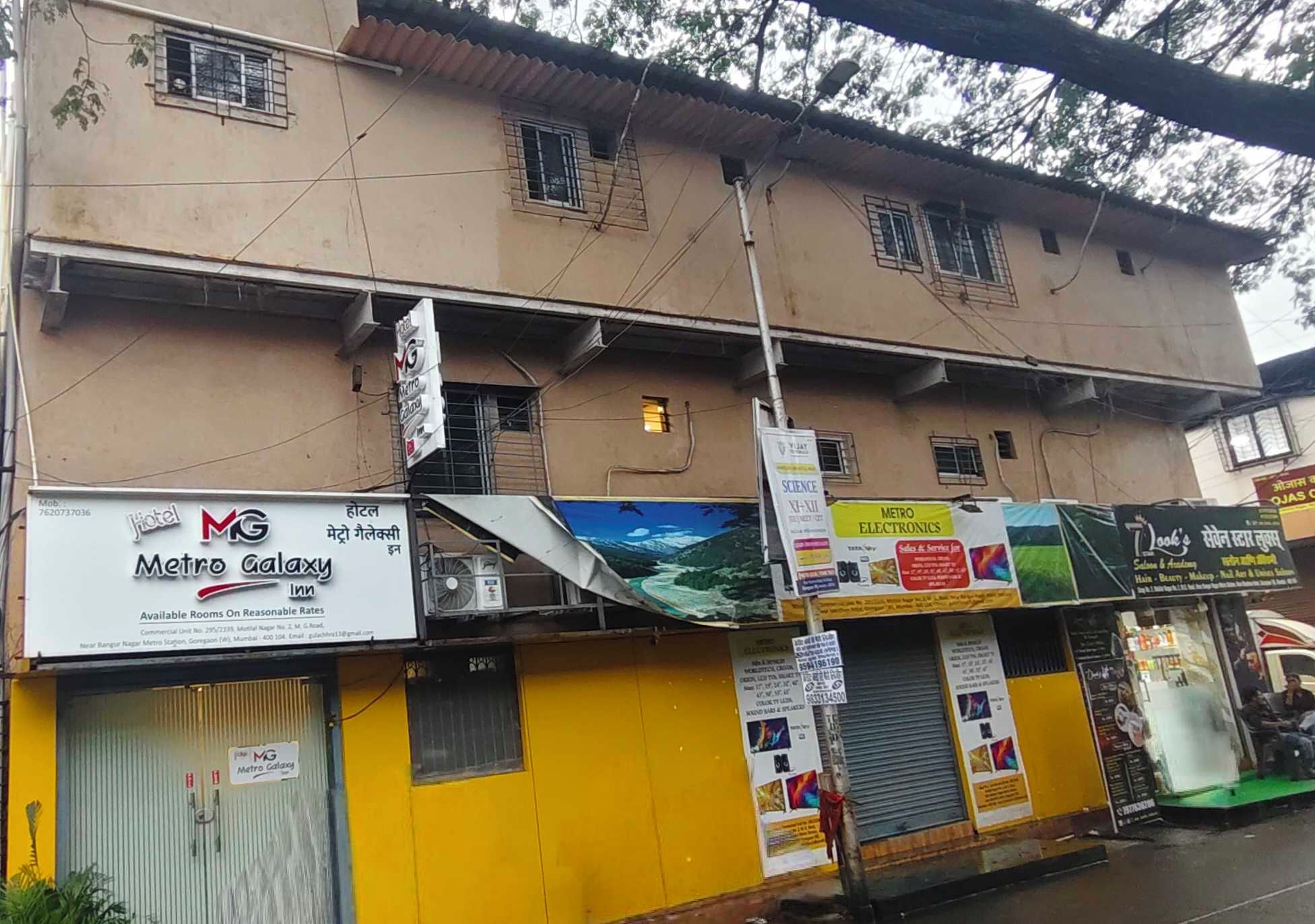 Un edificio con el letrero Metro Galaxy Inn, varias tiendas y una línea eléctrica visible.
