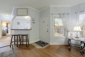 A clean, well-lit entryway with a wooden floor, a bench, a door with a 'No Smoking' sign, and a window with a view of the outside. - Great Location! Kissimmee Condo 5 Mi to Disney (Kissimmee)