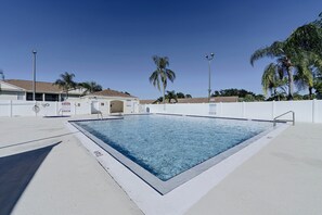 A rectangular swimming pool with a white deck, surrounded by a white fence, and palm trees in the background. - Great Location! Kissimmee Condo 5 Mi to Disney (Kissimmee)