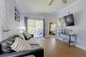 A living room with a leather sofa, a flat-screen TV, and a sliding glass door leading to a balcony. - Great Location! Kissimmee Condo 5 Mi to Disney (Kissimmee)