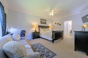 A bedroom with a bed, two bedside tables, a desk, a chair, a ceiling fan, and a view of the hallway. - Great Location! Kissimmee Condo 5 Mi to Disney (Kissimmee)
