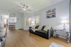 A living room with a black leather sofa, a dining table, a ceiling fan, and a painting on the wall. - Great Location! Kissimmee Condo 5 Mi to Disney (Kissimmee)