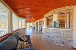 A spacious living area with a stone fireplace, a television, and a sofa with patterned cushions. - Near Hiking! Mtn-view Poolside Retreat in Phoenix (Phoenix)