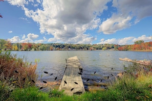 A wooden dock extending into a calm lake with autumn foliage in the background. - Lakefront Unit w/ Views, Near Colleges & Hospitals (Worcester)