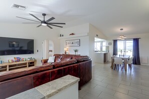 A spacious living room with a leather sofa, a flat-screen TV, and a ceiling fan. - Golf, Boat, Swim! Home w/ Lake Havasu & Mtn Views (Lake Havasu City)
