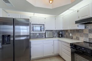 A modern kitchen with white cabinets, stainless steel appliances, and a stone backsplash. - Golf, Boat, Swim! Home w/ Lake Havasu & Mtn Views (Lake Havasu City)