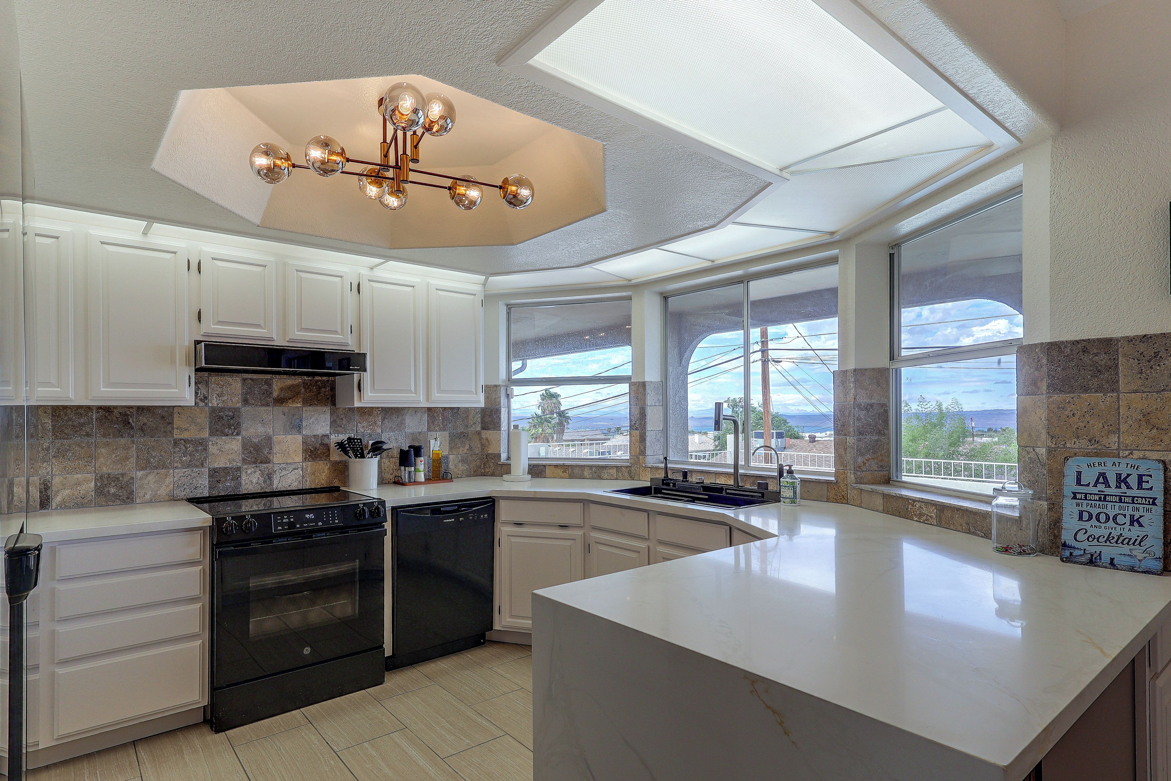A modern kitchen with a large island, built-in appliances, and a view of a lake.
